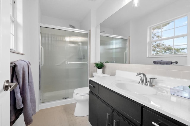 bathroom with vanity, toilet, decorative backsplash, and an enclosed shower