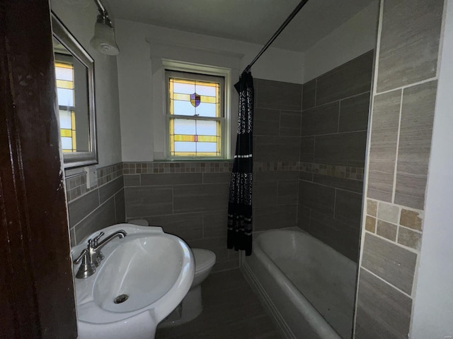 full bathroom featuring tile walls, shower / bathtub combination with curtain, sink, and toilet