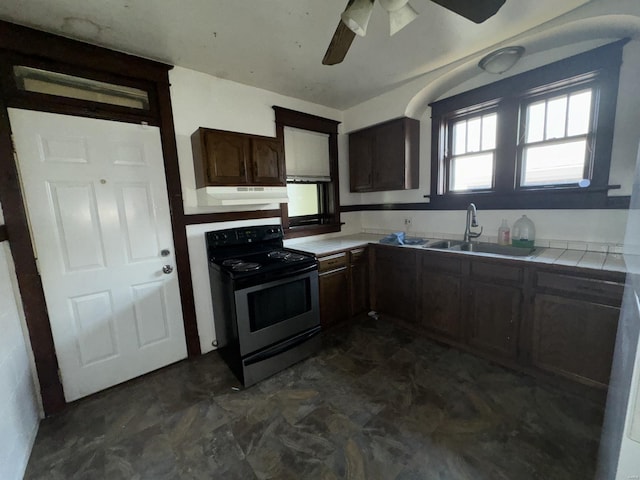 kitchen with electric stove, tile counters, ceiling fan, dark brown cabinets, and sink