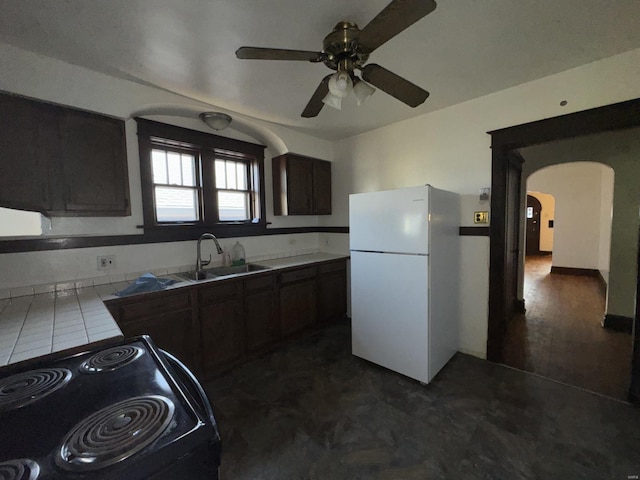 kitchen featuring tile countertops, white fridge, sink, black range with electric stovetop, and dark brown cabinetry