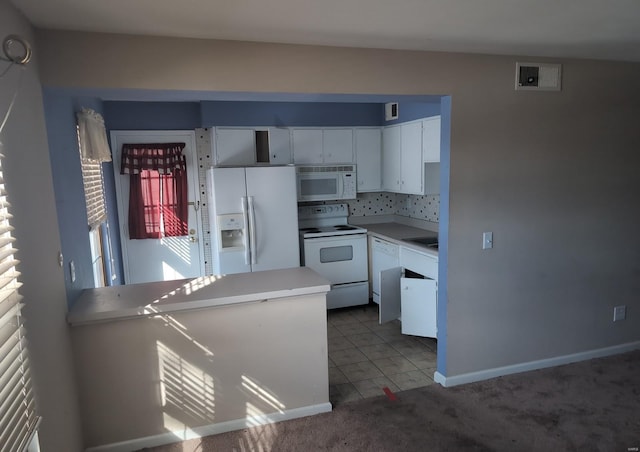 kitchen with white appliances, white cabinets, dark tile patterned flooring, and tasteful backsplash