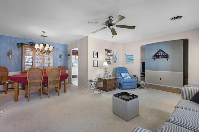 carpeted living room with ceiling fan with notable chandelier