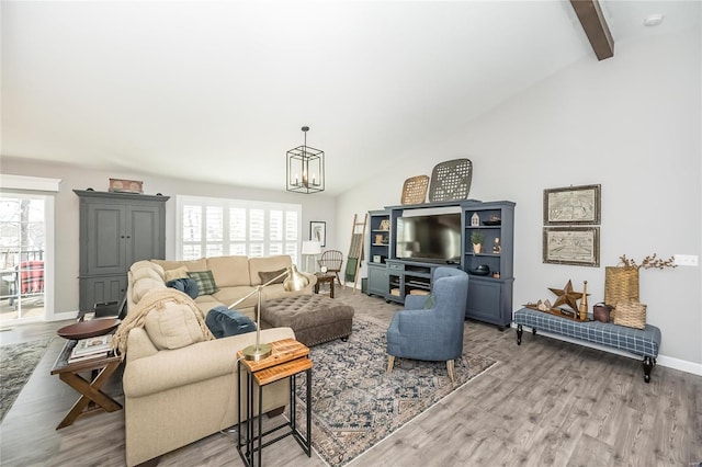 living room with a wealth of natural light, vaulted ceiling with beams, a chandelier, and light wood-type flooring