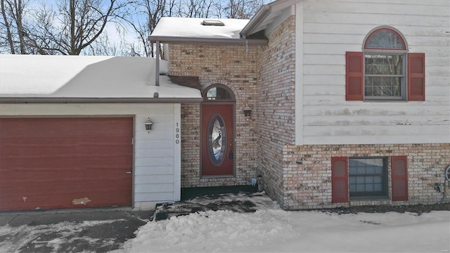 snow covered property entrance featuring a garage