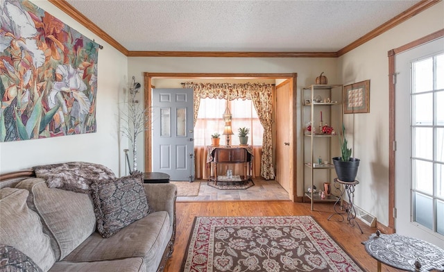 living room featuring ornamental molding, a textured ceiling, and light wood-type flooring