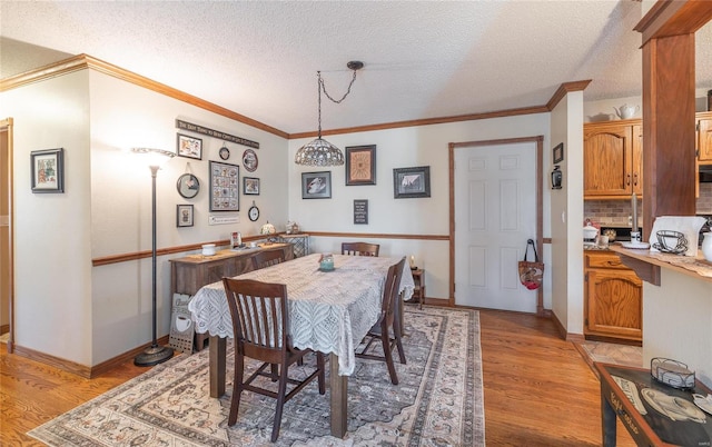 dining area with crown molding, light hardwood / wood-style flooring, and a textured ceiling