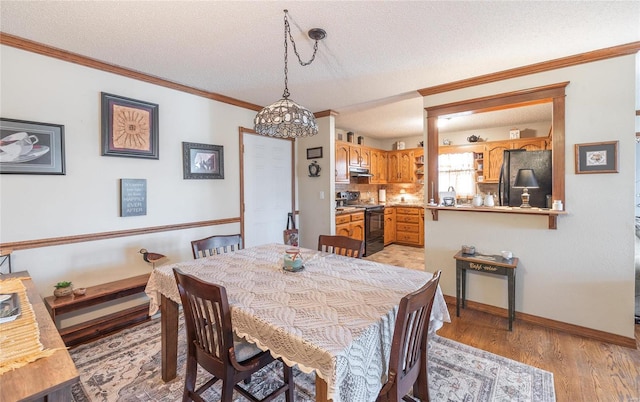 dining room featuring ornamental molding, light hardwood / wood-style floors, and a textured ceiling