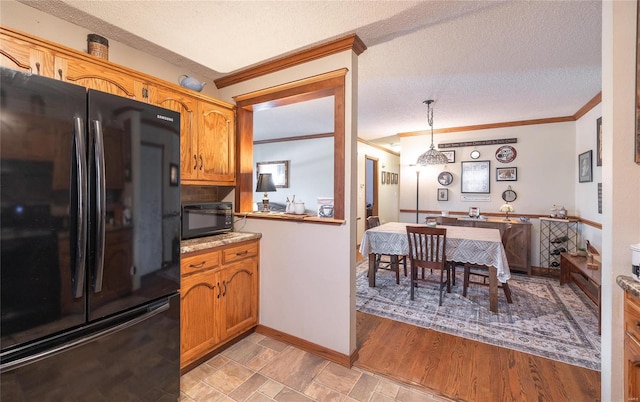 kitchen with pendant lighting, crown molding, a textured ceiling, and refrigerator