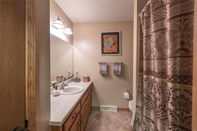 bathroom featuring vanity, a textured ceiling, and toilet