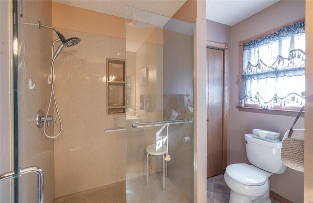 bathroom featuring a shower with door and toilet