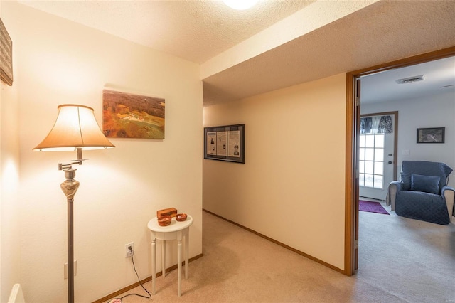 hall with light carpet and a textured ceiling