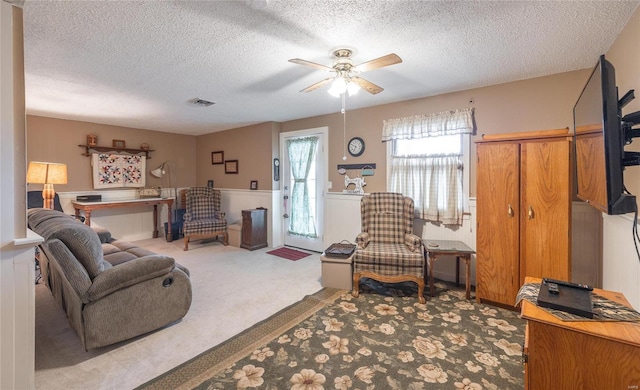 carpeted living room with ceiling fan and a textured ceiling