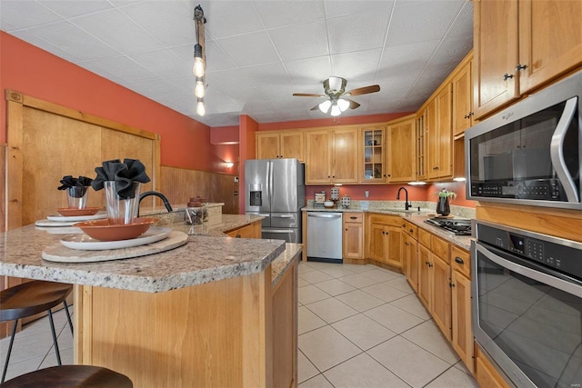 kitchen with a kitchen bar, sink, a center island, light tile patterned floors, and appliances with stainless steel finishes