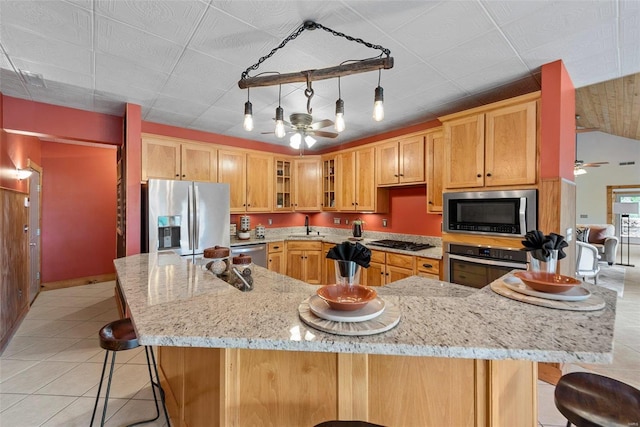 kitchen featuring ceiling fan, appliances with stainless steel finishes, a kitchen breakfast bar, and light stone countertops