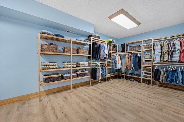 walk in closet with hardwood / wood-style flooring