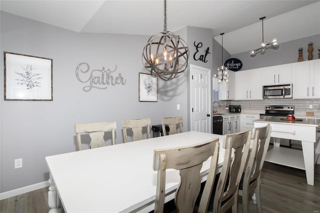 dining room with dark wood-type flooring, a chandelier, and vaulted ceiling