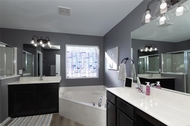 bathroom with hardwood / wood-style flooring, vanity, and plus walk in shower