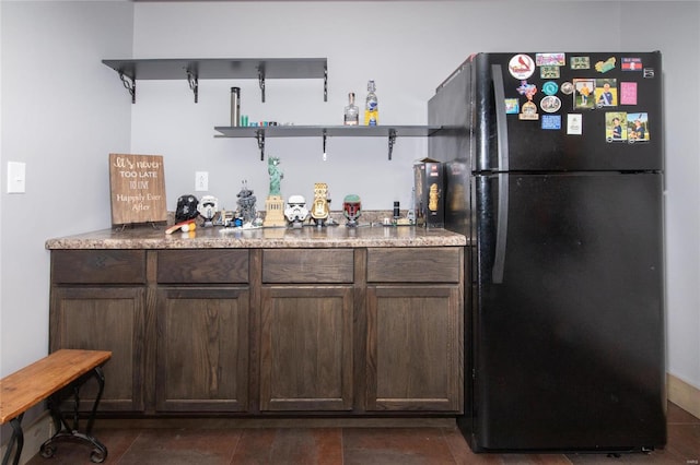 bar with black fridge and dark brown cabinets