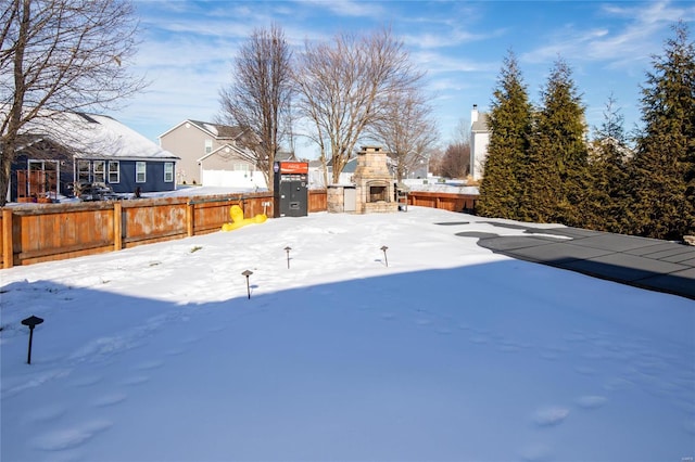 yard layered in snow featuring an outdoor stone fireplace