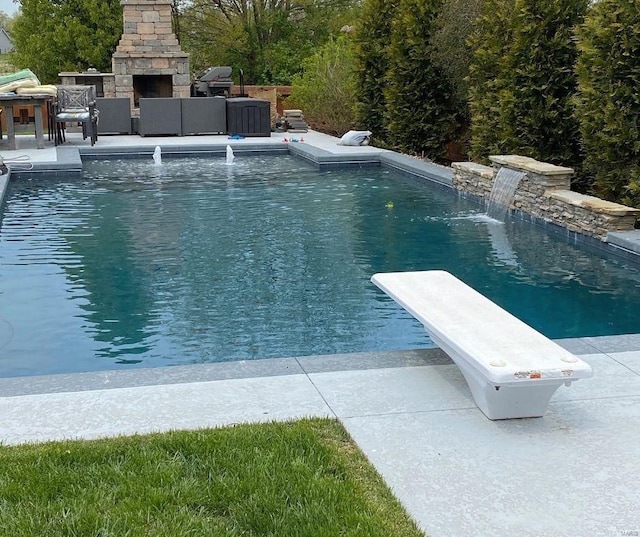 view of pool with pool water feature, an outdoor stone fireplace, a diving board, a patio, and area for grilling