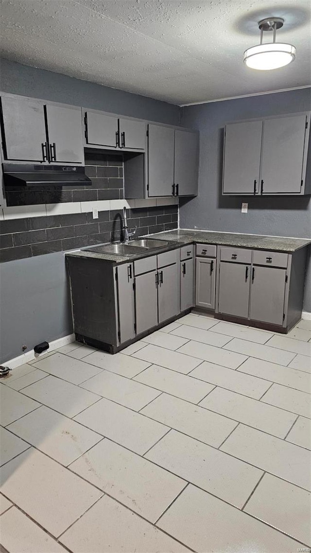 kitchen with tasteful backsplash, sink, gray cabinetry, and a textured ceiling