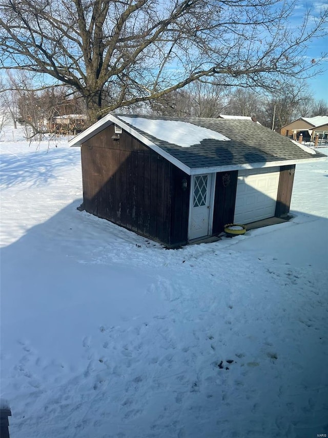 snow covered structure featuring a garage