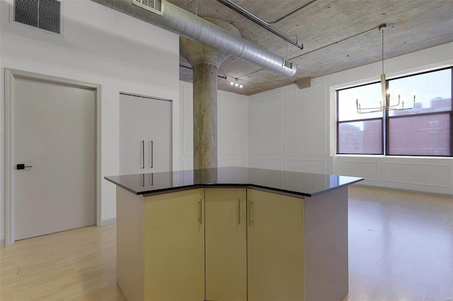 kitchen with an inviting chandelier, decorative columns, light wood-type flooring, hanging light fixtures, and a kitchen island