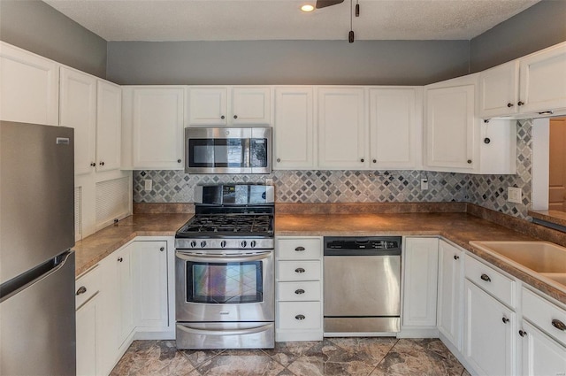 kitchen with backsplash, stainless steel appliances, a textured ceiling, and white cabinets