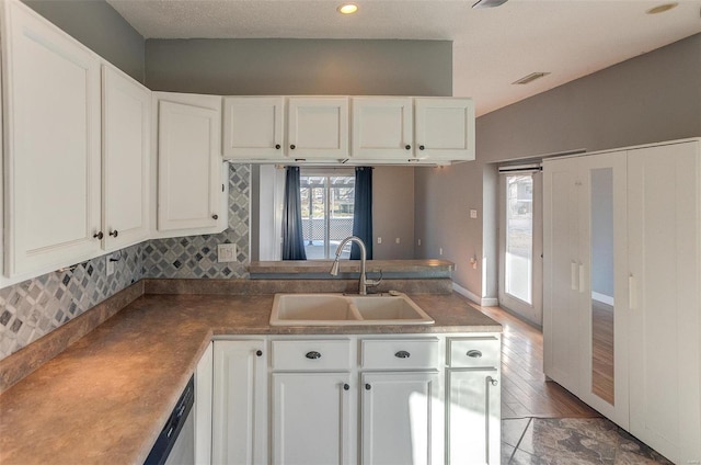 kitchen featuring backsplash, dishwasher, sink, and white cabinets