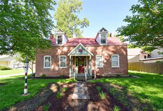 cape cod-style house with a front yard, fence, and brick siding