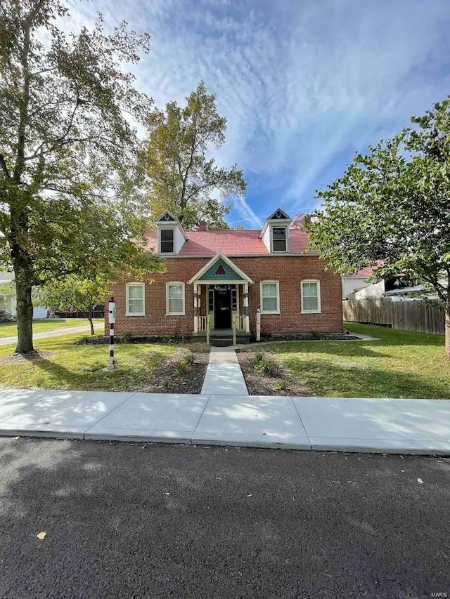 cape cod-style house featuring brick siding, a front lawn, and fence