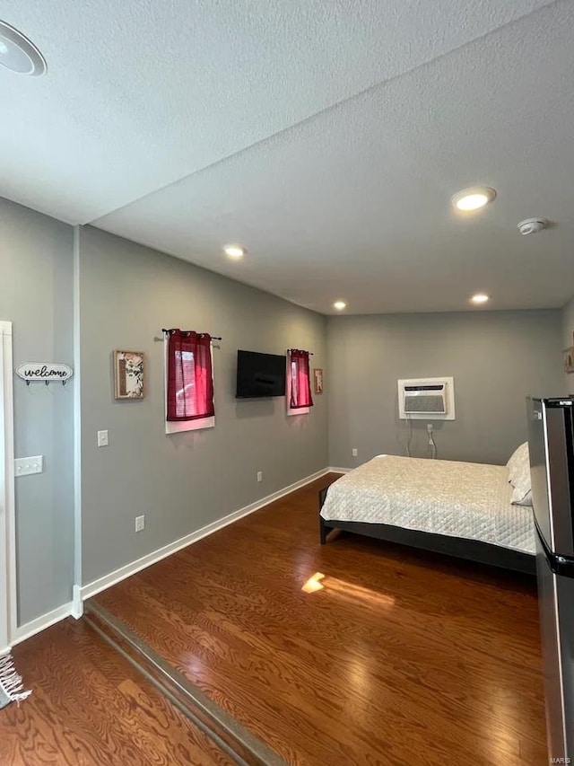 unfurnished bedroom with dark wood-type flooring, an AC wall unit, recessed lighting, and baseboards