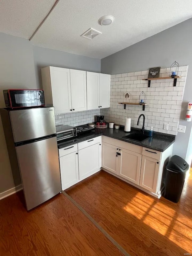 kitchen with dark wood finished floors, open shelves, freestanding refrigerator, a sink, and black microwave