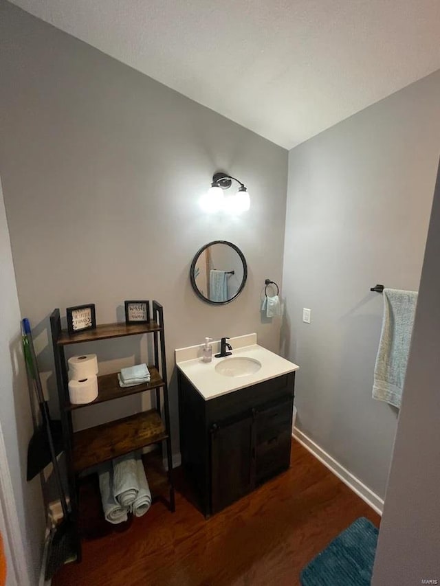 bathroom featuring baseboards, wood finished floors, and vanity