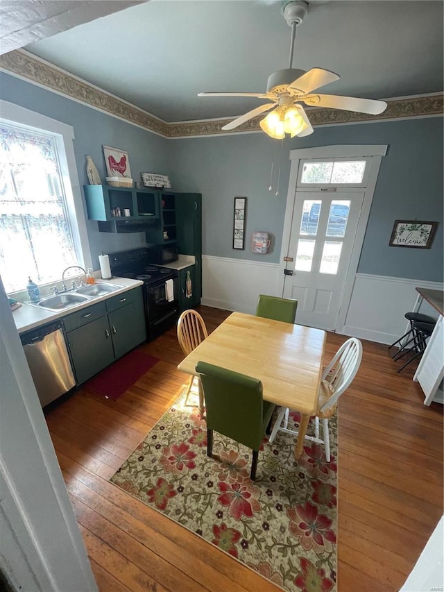 dining space with a ceiling fan, a healthy amount of sunlight, wainscoting, and hardwood / wood-style flooring