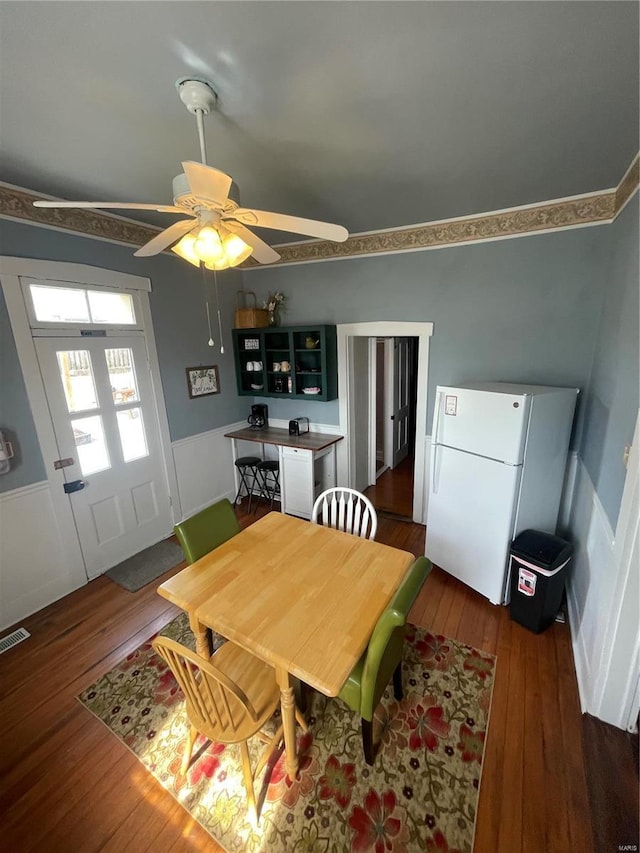 dining space featuring visible vents, a ceiling fan, and dark wood-style flooring