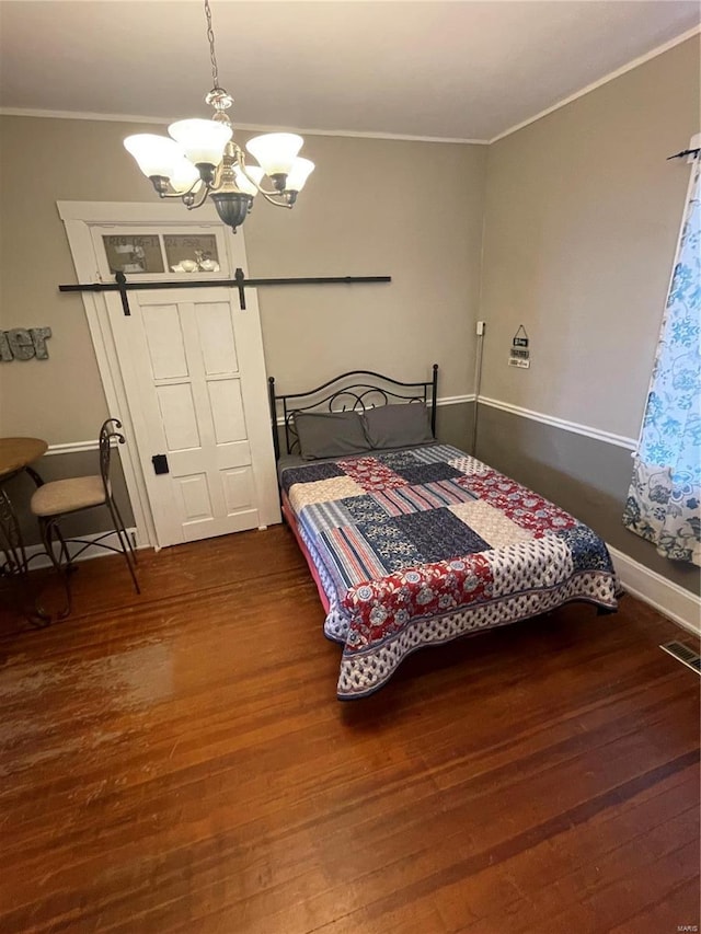 bedroom with visible vents, dark wood finished floors, crown molding, a barn door, and a notable chandelier