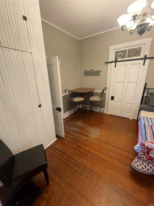 interior space with crown molding, wood finished floors, baseboards, and a chandelier