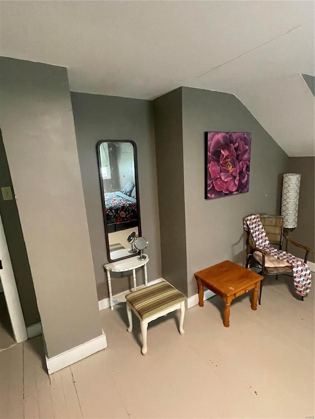 living area with lofted ceiling and baseboards