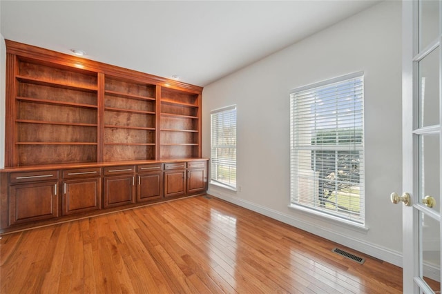 interior space featuring light wood-type flooring, visible vents, and baseboards