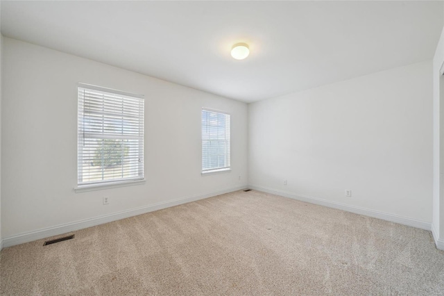 unfurnished room featuring light carpet, plenty of natural light, visible vents, and baseboards