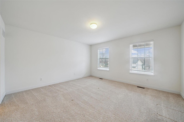 spare room with light carpet, visible vents, and baseboards