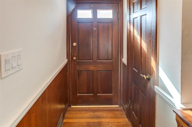 doorway to outside with dark wood-type flooring and wood walls