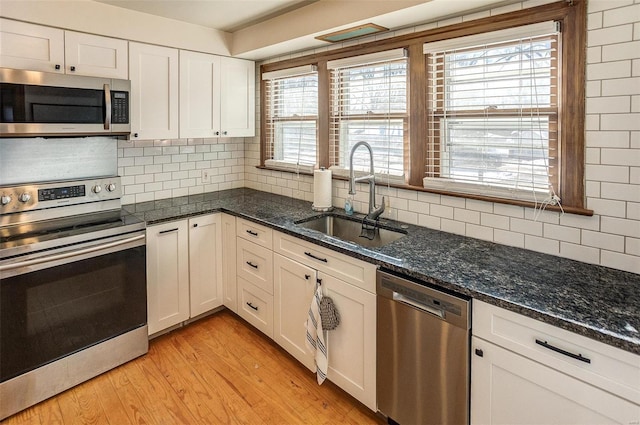 kitchen featuring decorative backsplash, appliances with stainless steel finishes, sink, and white cabinetry