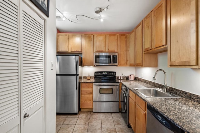 kitchen with appliances with stainless steel finishes, track lighting, sink, and light tile patterned floors