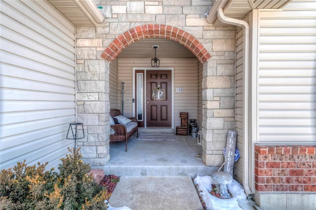 entrance to property featuring covered porch and stone siding