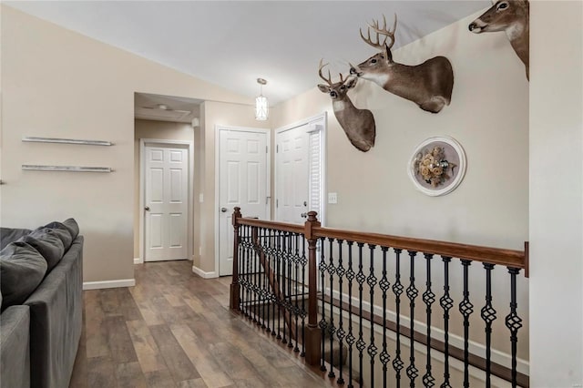 hallway featuring an upstairs landing, lofted ceiling, baseboards, and wood finished floors