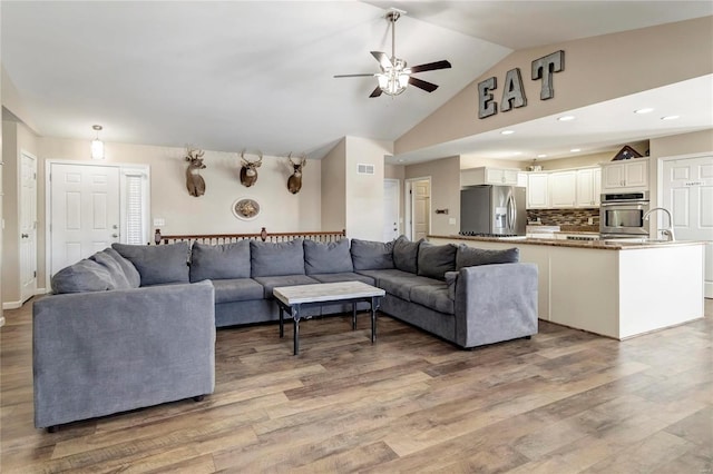 living area with recessed lighting, visible vents, light wood-style floors, a ceiling fan, and vaulted ceiling