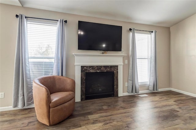 living room featuring a premium fireplace, wood finished floors, visible vents, and baseboards