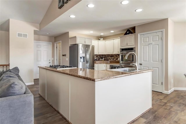 kitchen with visible vents, stainless steel appliances, decorative backsplash, and wood finished floors